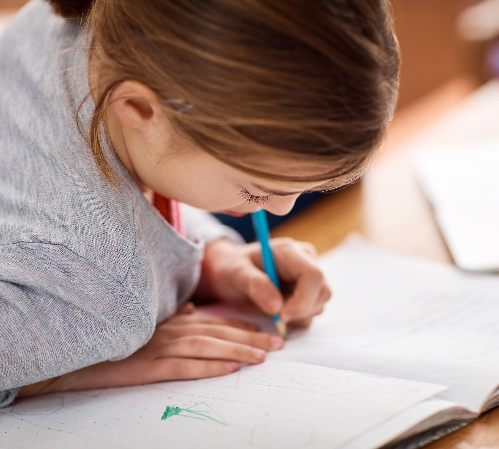 school girl writing in her notebook in class