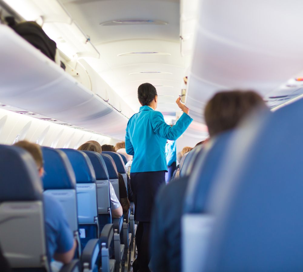 Interior of airplane with passengers on seats and stewardess