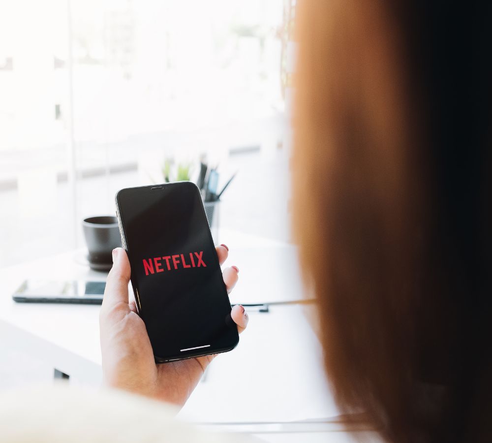 Woman hand holding Smart Phone with Netflix logo
