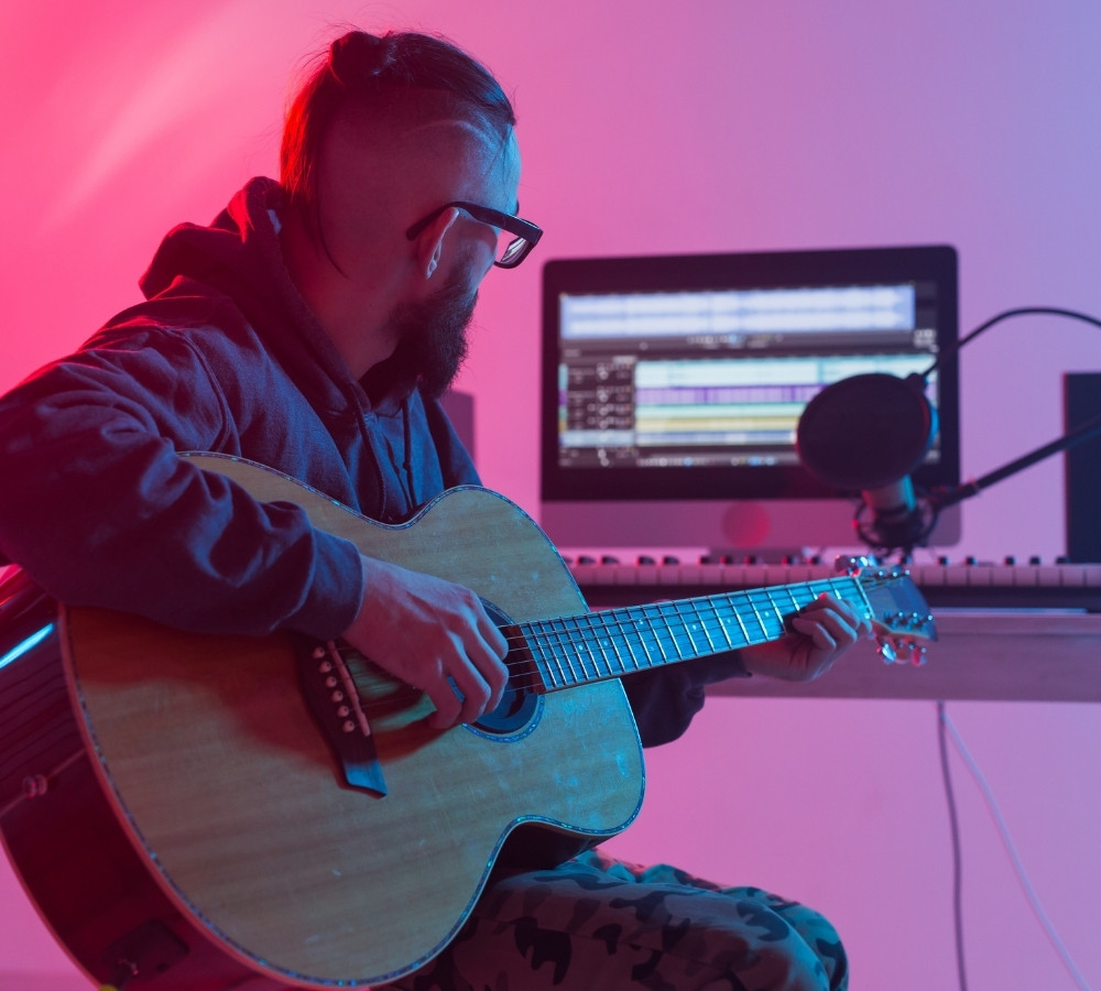 Guitarist recording electric guitar track in home studio
