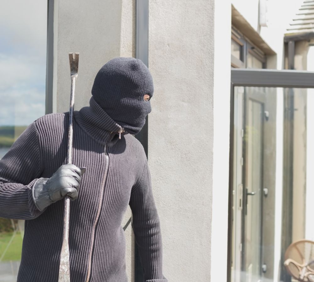 Robber hiding behind a wall with crow bar