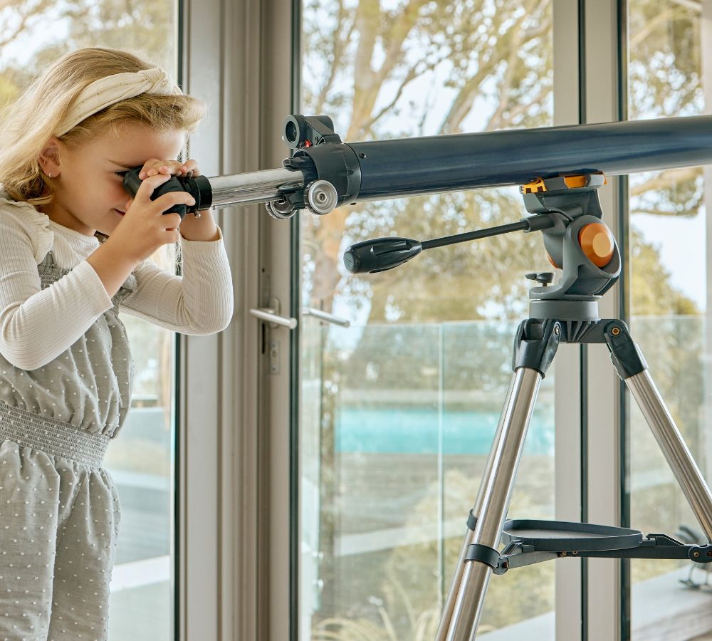girl looking at the sky or stars through a scope