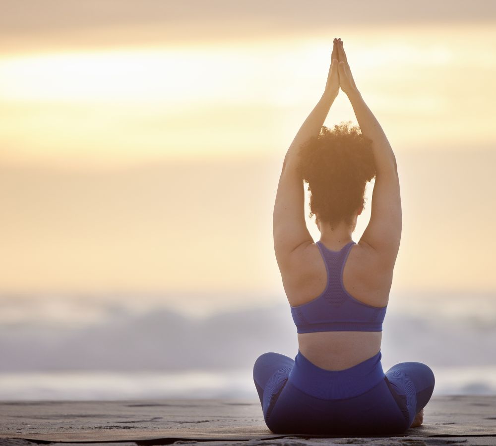 female doing yoga on the beach